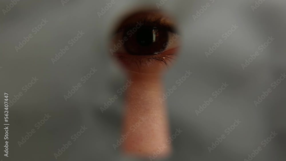 A man watches through the keyhole in the door. A man watches through the keyhole in the door.