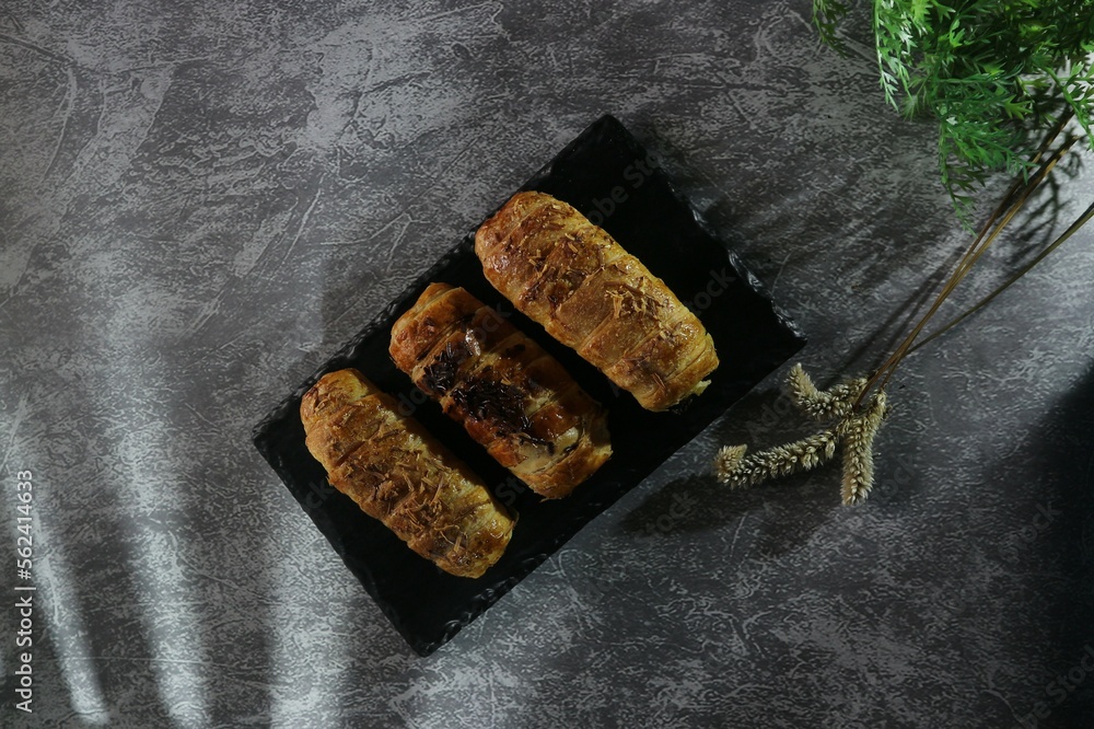 three sweet buns filled with banana and chocolate served on a black tray three sweet buns filled with banana and chocolate served on a black tray