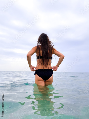  beautiful woman with long hair in a bikini dreamily looks at the beach and rests with the sea in the background