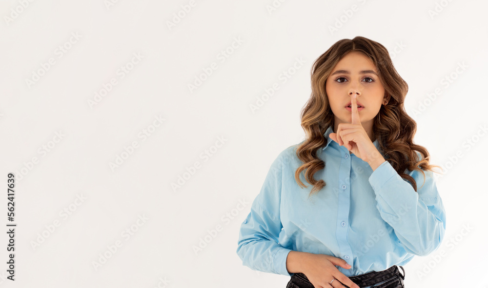 Shush, be silent! Serious lovely female asks to keep secret information confidential, dressed in blue oversized shirt, poses against white studio wall. Conspiracy concept Shush, be silent! Serious lovely female asks to keep secret information confidential, dressed in blue oversized shirt, poses against white studio wall. Conspiracy concept