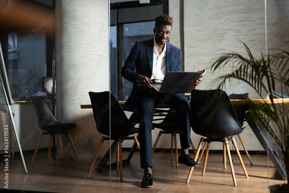 Portrait of successful businessman in office. Young smiling man using the laptop.. Portrait of successful businessman in office. Young smiling man using the laptop..