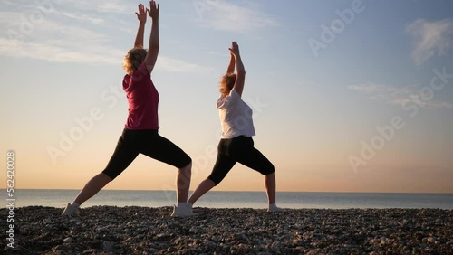 Two women doing yoga performing asanas and enjoying life on the beach sea, sunset time