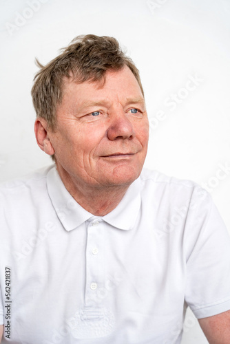 Portrait of peaceful thoughtful elderly man in white T-shirt looking away with inner smile on face