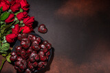 Chocolate hearts with red roses, gift box, on dark brown background copy space. Valentine's Day greeting card background