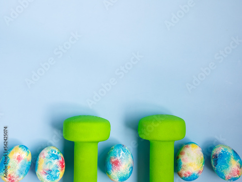 Canvas Print green heavy dumbbells, colorful easter eggs on blue background