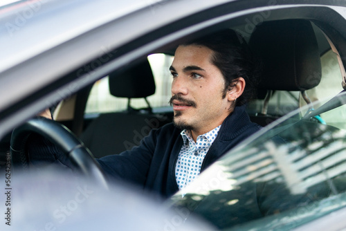 Young Hispanic male driver sitting in modern car photo