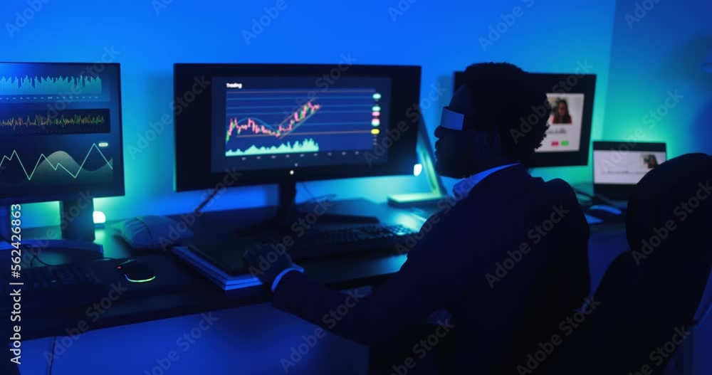 African trader working inside office at night time wearing virtual reality headset - Trading, metaverse and technology concept African trader working inside office at night time wearing virtual reality headset - Trading, metaverse and technology concept