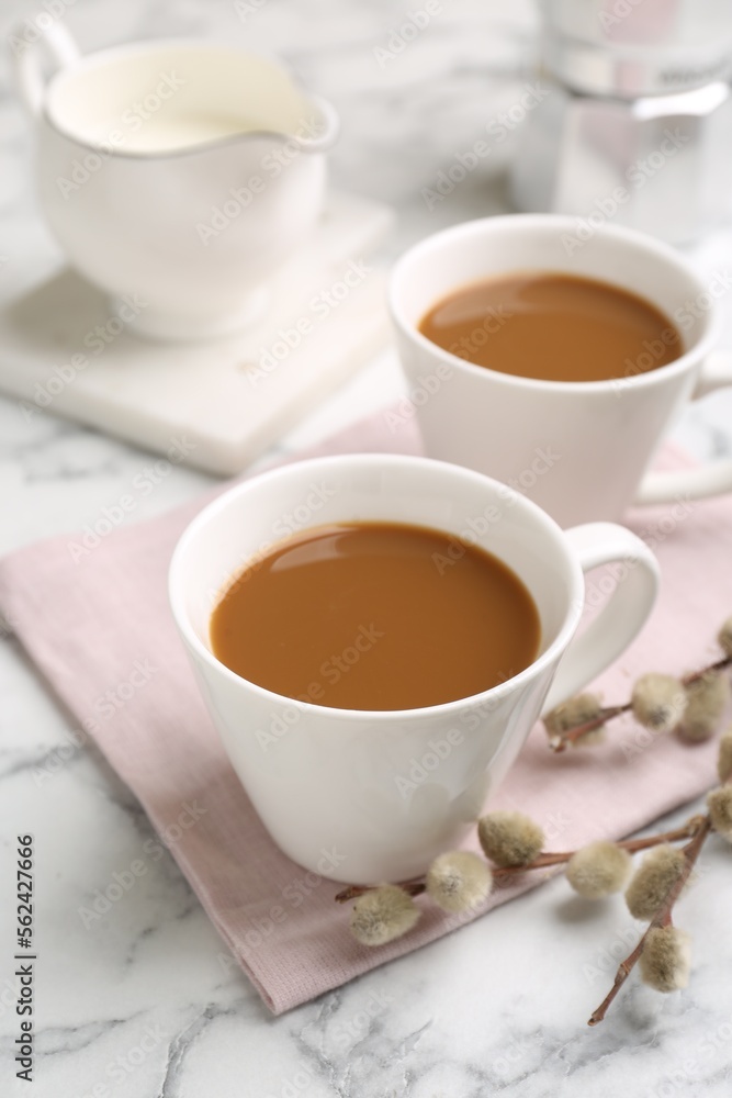 Cups of hot aromatic coffee and willow branches on white marble table Cups of hot aromatic coffee and willow branches on white marble table