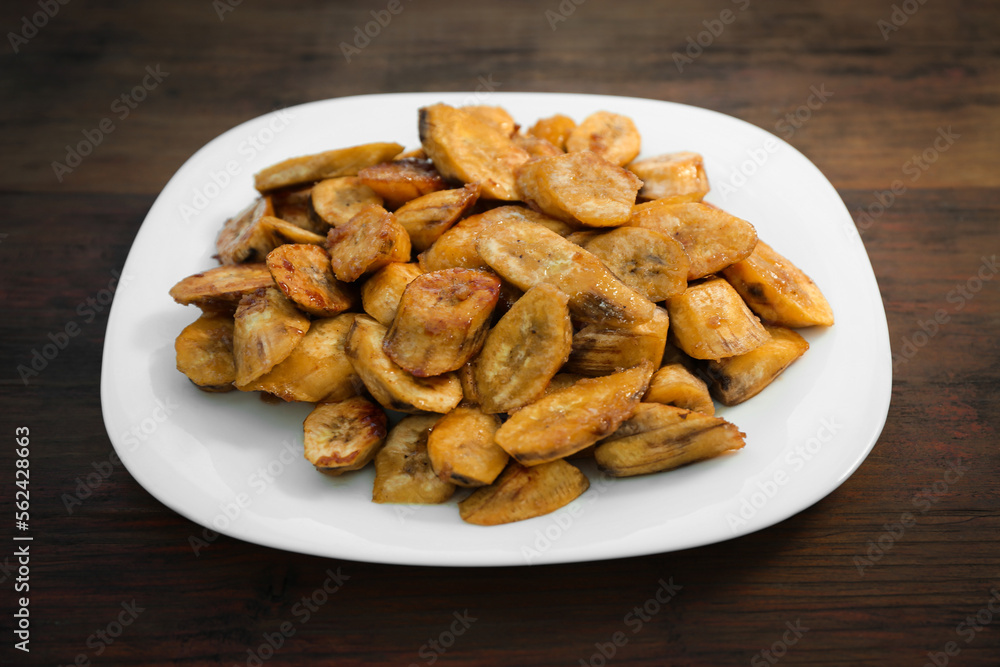 Tasty deep fried banana slices on wooden table