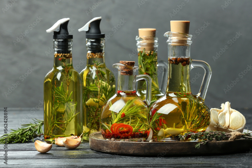 Cooking oil with different spices and herbs in bottles on grey wooden table Cooking oil with different spices and herbs in bottles on grey wooden table