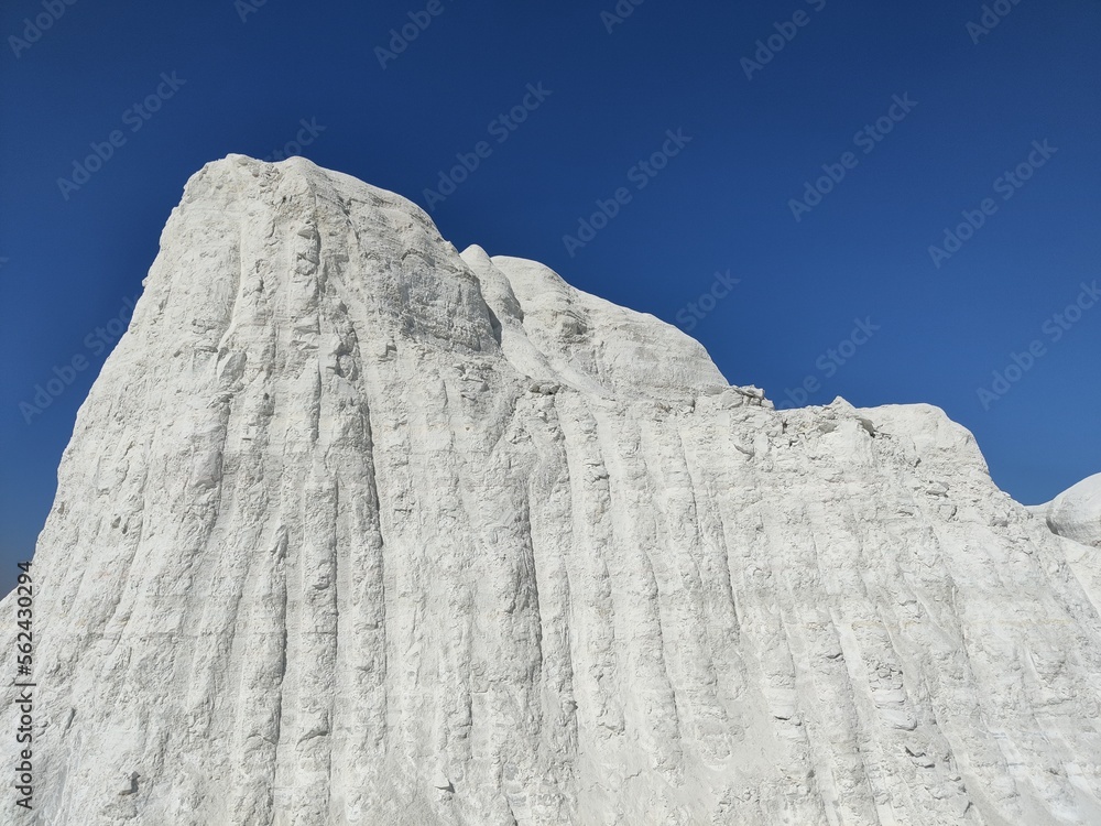 Picture of a big snow covered mountain with blue sky shot during sunlight. White snowy mountain hills, nature, landscape in winter Picture of a big snow covered mountain with blue sky shot during sunlight. White snowy mountain hills, nature, landscape in winter