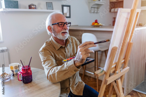 Senior man painting in his leisure time at home during the day. photo