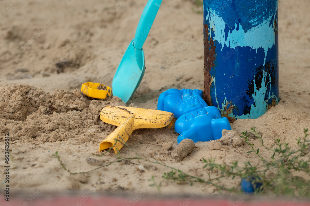 Children's toys in the sandbox.Forgotten dirty children's toys in an abandoned sandbox.The concept of destruction and despondency. Children's toys in the sandbox.Forgotten dirty children's toys in an abandoned sandbox.The concept of destruction and despondency.