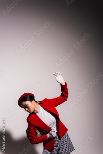 Trendy asian model in white gloves posing on grey background with shadow