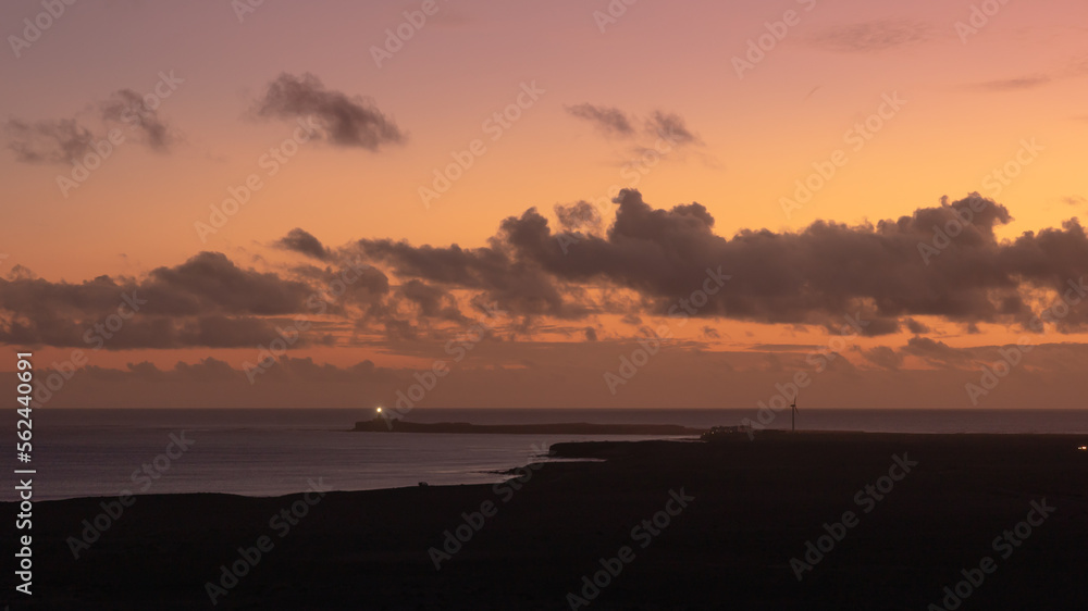 Orange sunset over the sea with a watchtower in the background in Jandia, Fuerteventura