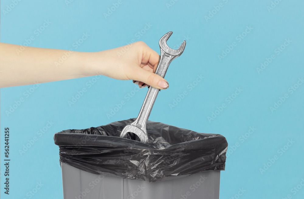 throw away wrench in trash can, wrench in hand in front of trash can