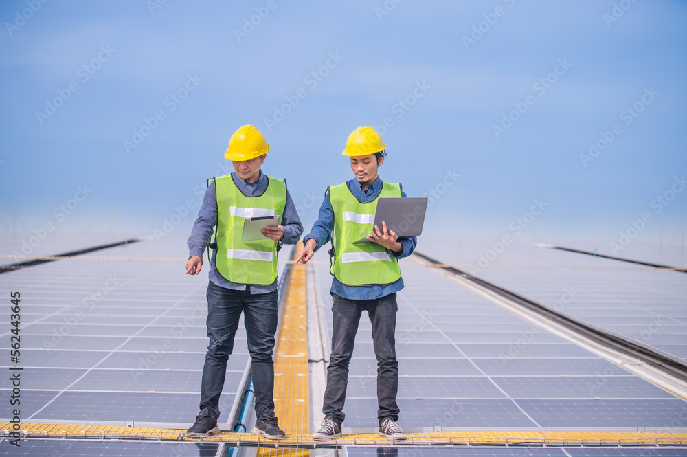 Asian engineer using tablet checking in solar power system for industrial ecology control top roof factory Asian engineer using tablet checking in solar power system for industrial ecology control top roof factory