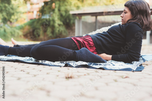 Athletic woman in sportswear doing fitness yoga stretching exercises outdoors park