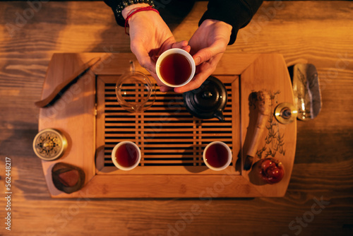 Man's hands holding cup with chinese tea. View from above at the wooden table with traditional chinese tea ceremony accesories and cups of tea photo