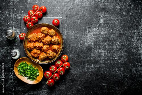 Meat balls with tomatoes and chopped greens in a bowl.