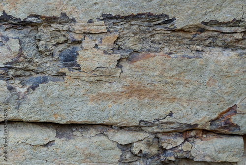 The gray limestone background has cracked and peeled off the bedrock, exposing the inner rock in different colors depending on the minerals that make up the rock. abstract background.