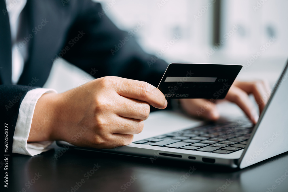 Close up of young businesswomen using credit card shopping online via laptop computer at home office, modern lifestyle, digital banking, cashless, E-commerce concept. Close up of young businesswomen using credit card shopping online via laptop computer at home office, modern lifestyle, digital banking, cashless, E-commerce concept.