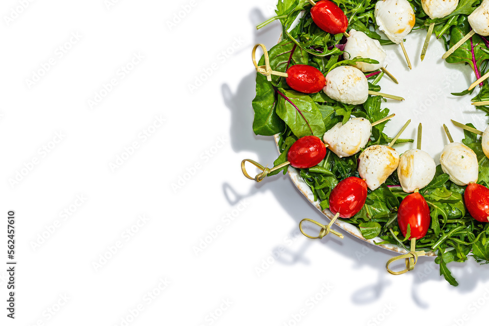 Charcuterie wreath isolated on white background. Mozzarella, cherry tomatoes, and arugula on skewers. Fashionable snacks, festive vegetarian food, trendy hard light, dark shadow Charcuterie wreath isolated on white background. Mozzarella, cherry tomatoes, and arugula on skewers. Fashionable snacks, festive vegetarian food, trendy hard light, dark shadow