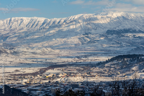 Winter landscape, covered with snow. Panorama of Gjirokastër (Gjirokaster), Albania, with the gorgeous Mali i Gjerë mountains that surround the city.