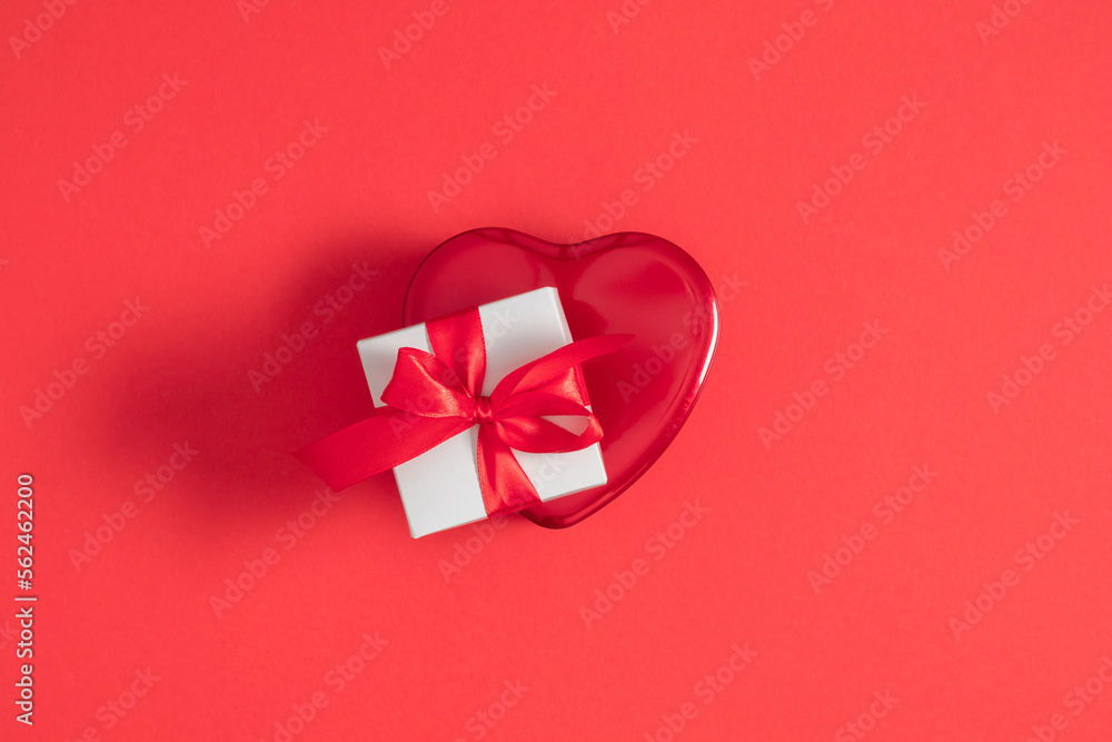 Valentine's Day background. Red box in shape of heart and gift box with red bow on isolated red background. Valentine's day concept. Flat lay, top view, copy space