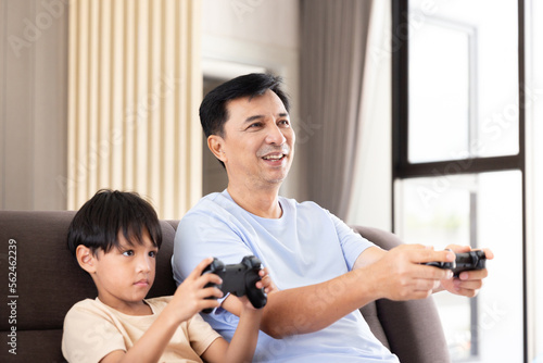 Happy father dad and son play video game station with control game by remote joystick technology for family entertainment activity during weekend