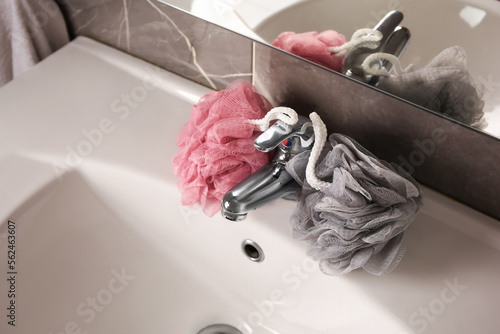 Colorful shower puffs between faucet on sink in bathroom, above view