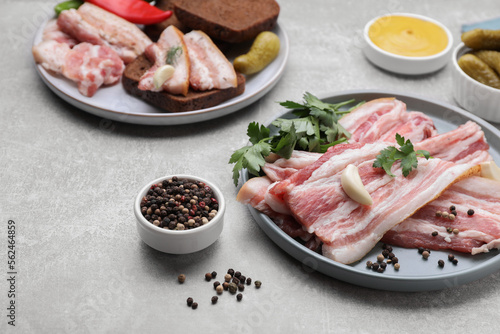 Slices of tasty pork fatback with spices on grey table