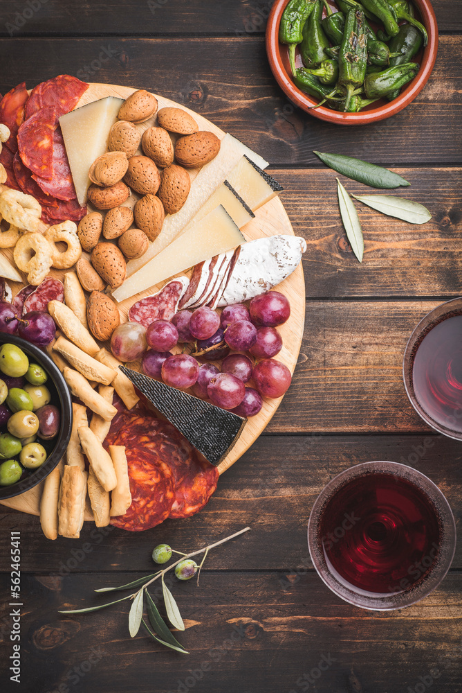 Appetizers boards with assorted  delicatessen cheese, salami, grape and nuts. Charcuterie and cheese platter, Spanish style and ingredients: olives, Pimientos, Chorizo, picos, cheese Semicurado - obrazy, fototapety, plakaty 