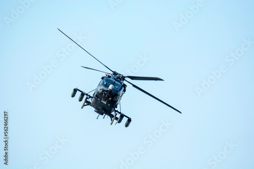 Combat helicopter is flying against isolated blue sky. Combat helicopter attack enemy.