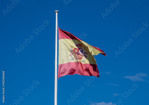 Spanish flag waving in the wind hanging on a pole.