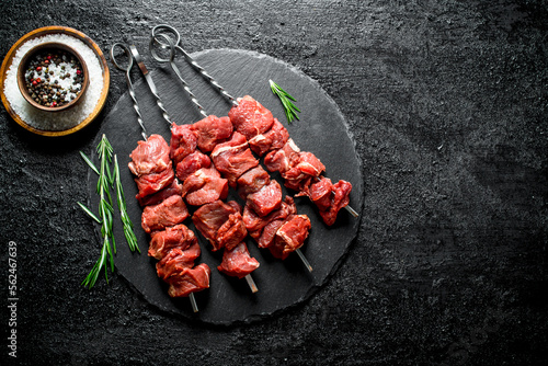 Raw kebab on a stone Board with rosemary and spices.