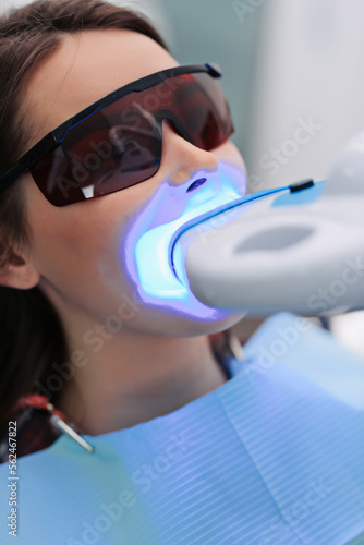 Girl patient in the dental clinic. Teeth whitening UV lamp. photo