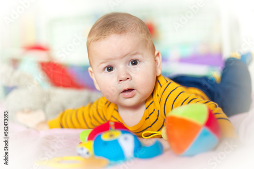Baby plays with toys. Close-up view of cute baby boy lies on its stomach and play with toy. Playground for babies