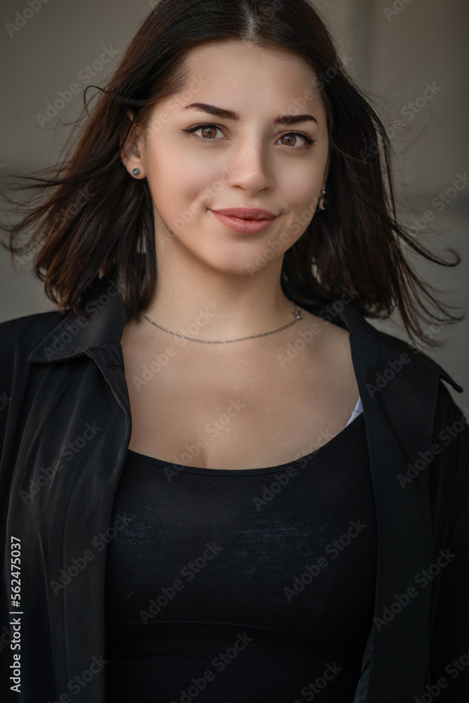 Dramatic close-up portrait of a dark-haired beautiful young girl on a gray background. Dramatic close-up portrait of a dark-haired beautiful young girl on a gray background.
