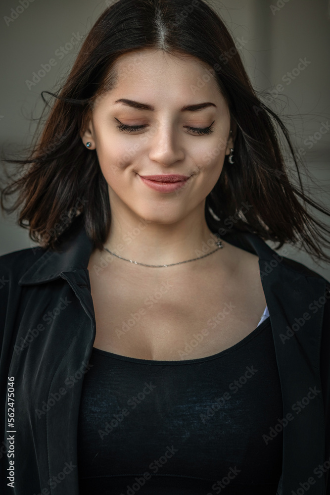 Dramatic close-up portrait of a dark-haired beautiful young girl on a gray background. Dramatic close-up portrait of a dark-haired beautiful young girl on a gray background.