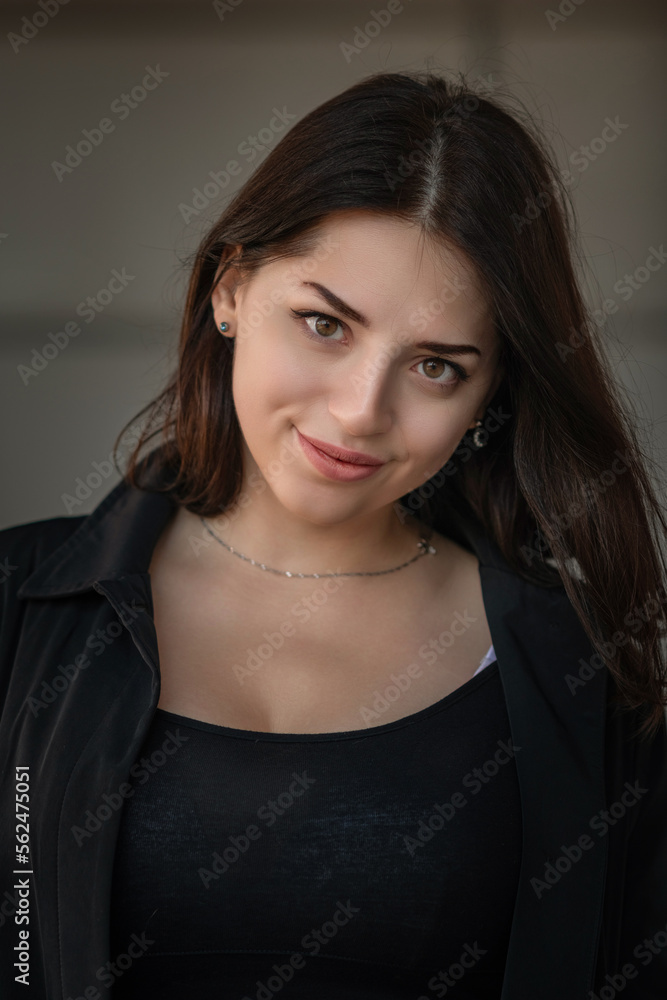 Dramatic close-up portrait of a dark-haired beautiful young girl on a gray background. Dramatic close-up portrait of a dark-haired beautiful young girl on a gray background.