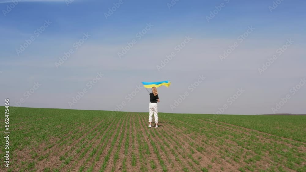 A blonde women is waving Ukrainian flag, as a sign of victory and peace, on a sky and a spring field background. High quality 4k footage A blonde women is waving Ukrainian flag, as a sign of victory and peace, on a sky and a spring field background. High quality 4k footage
