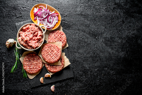 Raw burgers with ground beef and sliced onions in bowls.