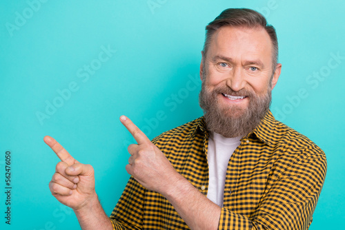Photo portrait of mature age promoter man wearing trendy yellow shirt point fingers empty space novelty info isolated on aquamarine color background
