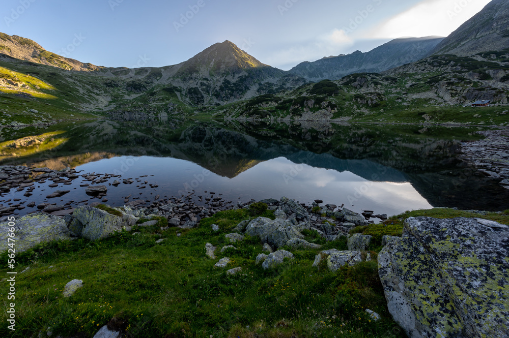 Lake and mountains in Romania's Retezat mountain range in the Carpathians of Transylvania with the mountain reflected in the lake's surface stones Lake and mountains in Romania's Retezat mountain range in the Carpathians of Transylvania with the mountain reflected in the lake's surface stones
