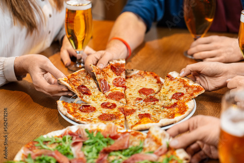 leisure  food and drinks  people and holidays concept - close up of friends eating pizza and drinking beer at restaurant or pub