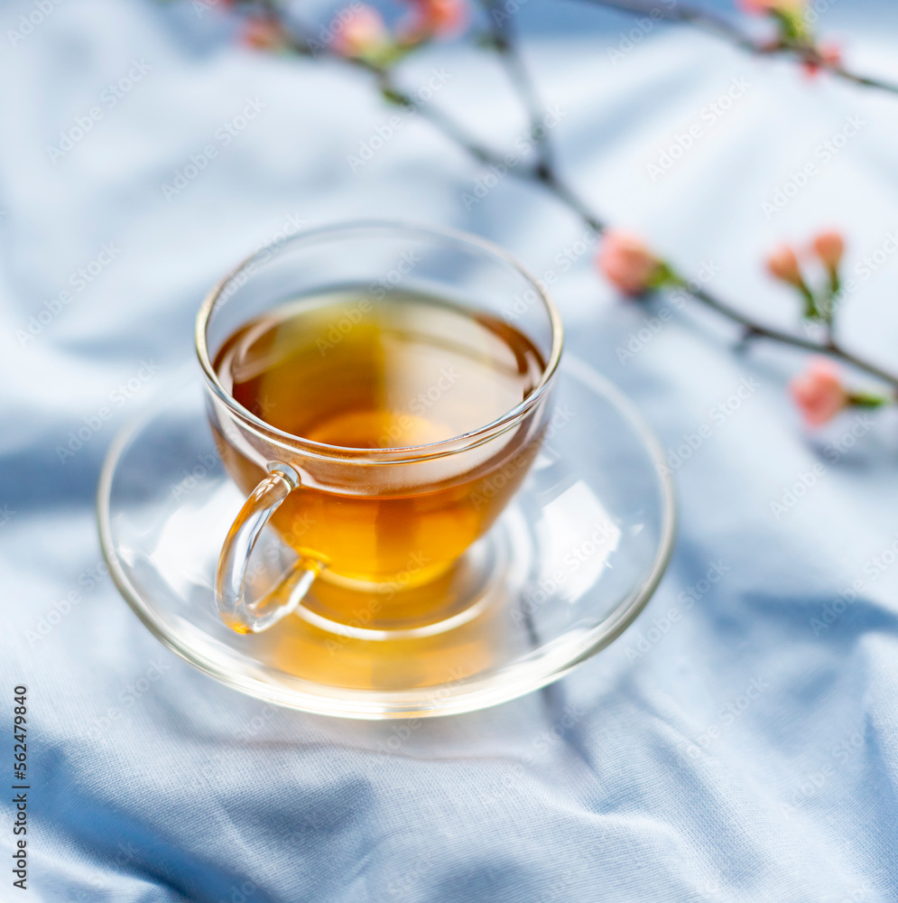 Spring morning breakfast concept with a cup of green tea on the blue bed sheets. Close up Spring morning breakfast concept with a cup of green tea on the blue bed sheets. Close up