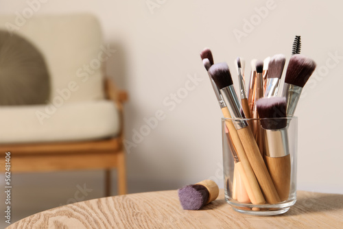 Set of professional makeup brushes on wooden table indoors, space for text