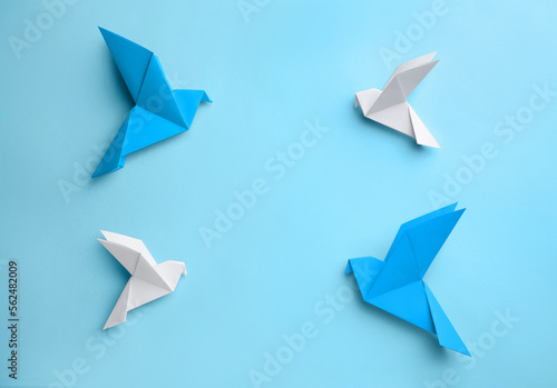 Origami art. Colorful handmade paper birds on light blue background, flat lay. Space for text