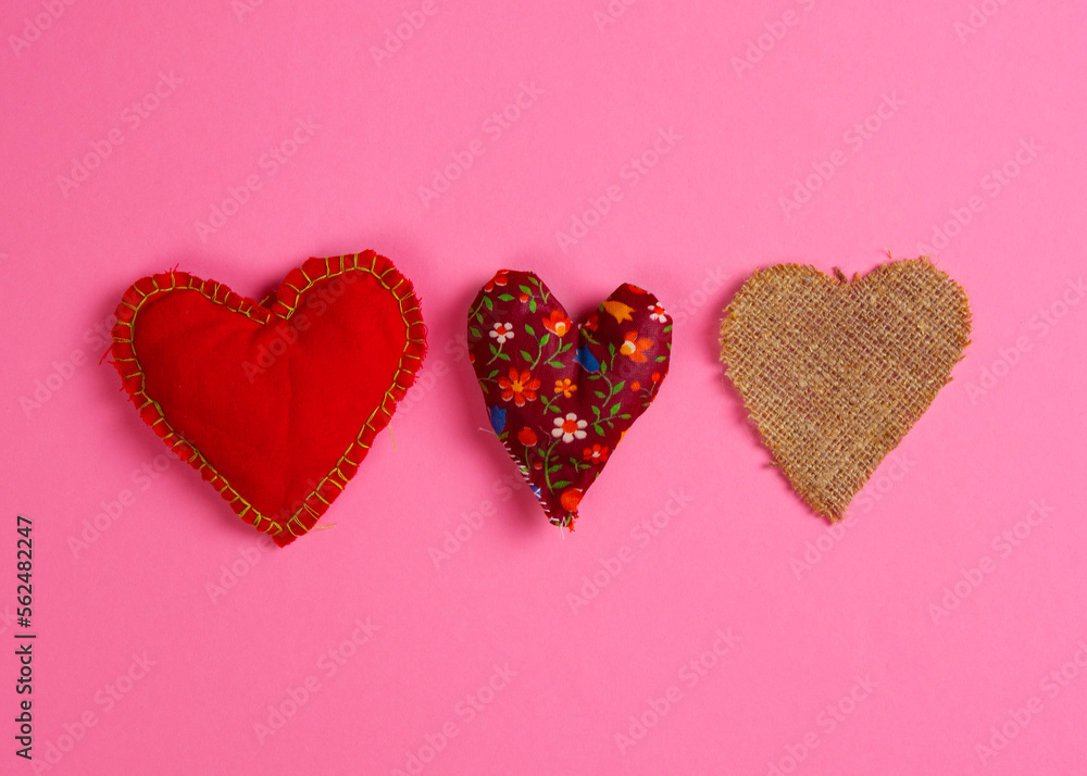 Three fabric hearts on a magenta background. Horizontal arrangement. Flat lay